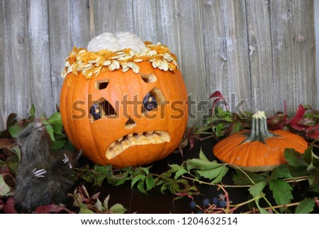 A carved pumpkin with it's brain showing and a toy rat standing in front of the pumpkin