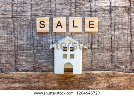 Miniature toy model house with inscription SALE letters word on wooden backdrop. Eco Village, abstract environmental background. Real estate mortgage property insurance sweet home ecology sale concept
