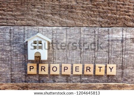 Miniature toy model house with inscription PROPERTY letters word on wooden backdrop. Eco Village, abstract environmental background. Real estate mortgage property insurance sweet home ecology concept