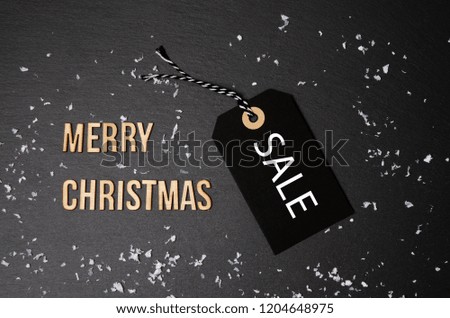 Merry Christmas black background and price label.  Black Friday. Sales concept. Copy space.  Paper label against a dark grey background. Black Friday shopping sale concept with ticket Sale tag