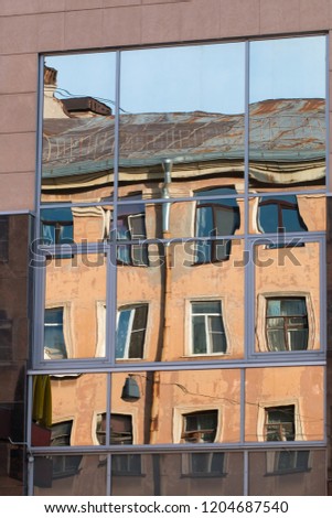 Reflection of an old classic building in the windows of a modern building.  Modern office building window with reflection of an old apartment building. Cleaning windows in old and new buildings.