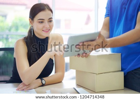 Fast and reliable service. Caucasian woman signing on tablet pc computer at home office. Delivery man brings delivering parcel box.                               