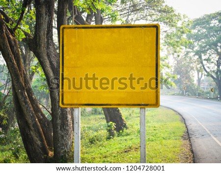 Yellow old blank road sign empty on the roadside with tree background