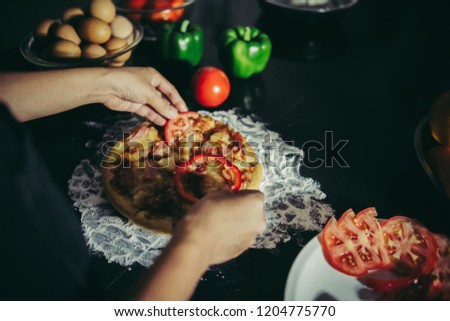 Close up of woman hand put topping on homemade pizza.