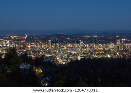 Portland Oregon downtown skyline at evening blue hour with Mt Hood in the distance.