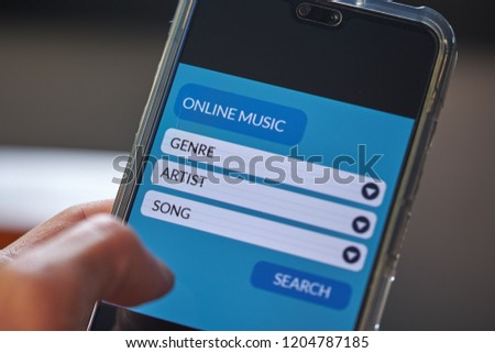 Online music concept. Male hands using smart phone searching for songs on music streaming application website screen. Front view and close up photo. All screen graphics are made up with own design.
