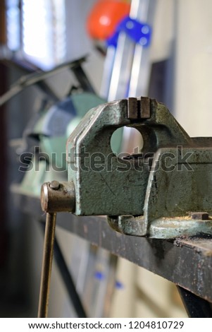Vise close up on metal workshop. Bench grinder on background. Vertical image.