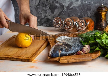 The process of slicing lemon for cooking Dorad. Female hands closeup. The concept of homemade food, culinary hobby Royalty-Free Stock Photo #1204866595