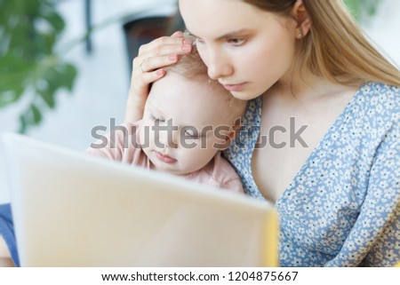 Close up portrait of cheerful lovely mother gently and carefully hugs her children and together with kid looks at children's tales or cartoons on laptop. Mom calms the child with gadgets. Parenthood