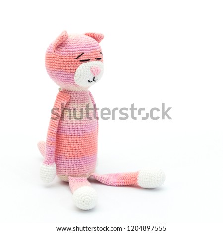 Sitting pink crochet cat on white background