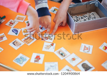children hands touching white cards of letters numbers and pictures for little kids on the blue table. Time to learn. Education concept. Top view.