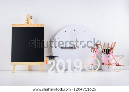 2019 happy new year / graduate study abroad program, time schedule arrangement, education concept : Black graduation cap of success on number 2019 white wood cut, clock on student desk, office table