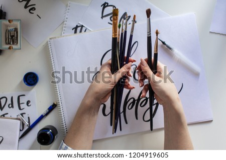 top high angle view of woman artist painter hold in hand bunch of different types of paint brushes