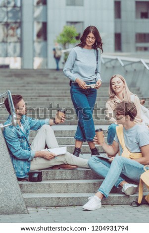friends with coffee to go resting on street steps in new city