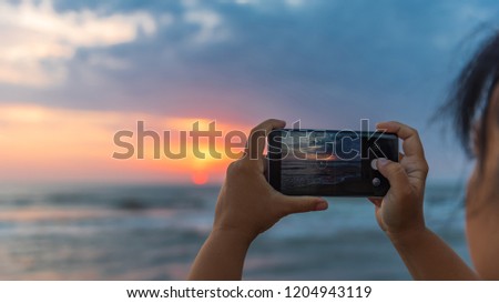 Girl takes pictures on smartphone dawn on the sea