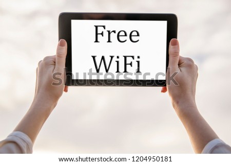 Free zone wi-fi concept. Tablet with free wifi icon in woman's hands on sky natural background. Free access to wi-fi outdoors.