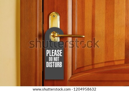 Closed door with sign PLEASE DO NOT DISTURB on handle at hotel.