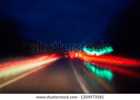 Night traffic on the road in rainy weather. Blurred background.