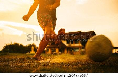 An action sport picture of a kids playing soccer football for exercise in community rural area under the sunset. Close up while shooting action.
