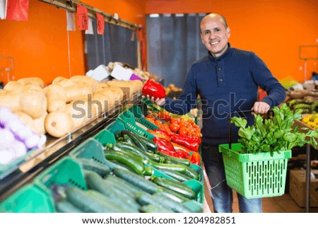 Joyful smiling elderly man buying seasonal vegetables in local grocery
