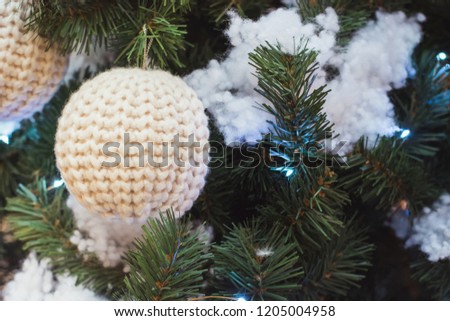 Christmas tree with knitted white ball as decor with copy space on blurred bokeh. Close up. Xmas.