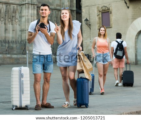 Woman and man tourists are holding camera in hands and photographing in city. 