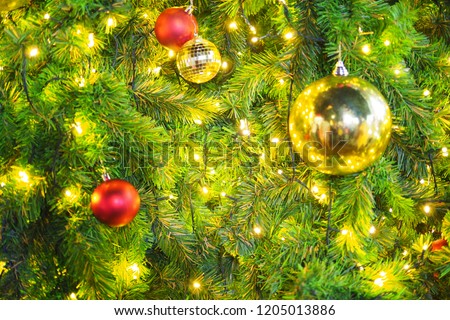 The blurred picture is the big Christmas tree have many decorations. The decorations are red and gold balls, blinker.