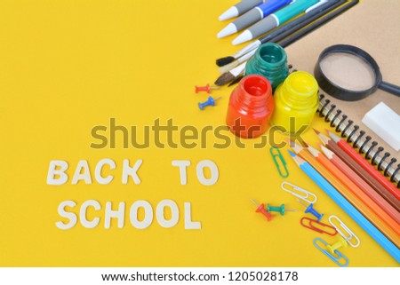 Flat lay image from above: school supplies on yellow background with copy space for text. Back to school concept.