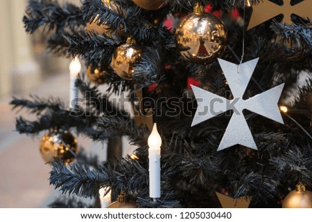Christmas tree with gothic dark decor, golden balls, candles on dark in interiors. Xmas. Close up. Copy space.