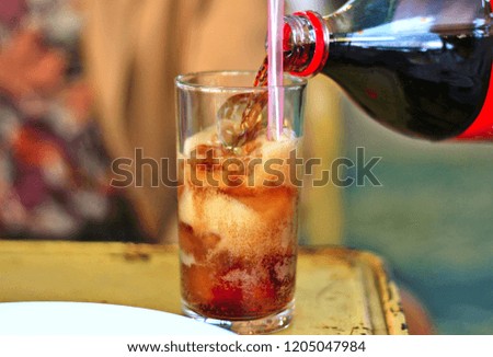 Children are pouring soft drinks in glass. With ice inside