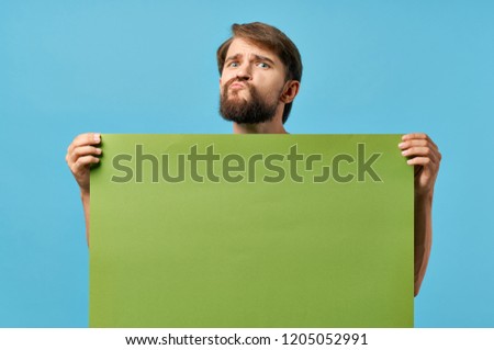 man grimaces and holds green layout                       