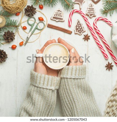 Christmas, New Year background. Flat-lay,glittering toys, female hands with mug of hot lat, cinnamon, scissors, over white wooden table, top view