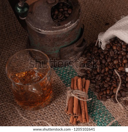 still life of an old coffee grinder with coffee. Sliced from a glass of whiskey, cinnamon and scalded coffee
