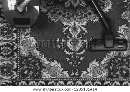 electric vacuum cleaner on the background of an old carpet, top view of flat lay, black and white photo