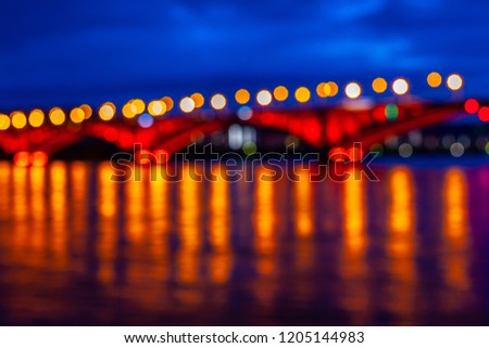 Defocused background, night lights from the bridge on the river