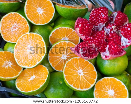 close up of sliced pomeranate lays on vivid cutted oranges, juicy exotic fruits