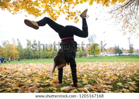 Autumn photo of sporty Young woman in black jacket stretching in forest at morning against background of trees. Staying in the hands