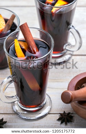 Hot mulled wine with spices and orange on wood background. Vertical picture.