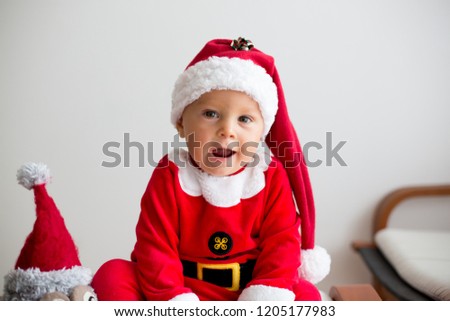 Cute toddler child, boy, playing with christmas decoration at home, dressed in Santa costume