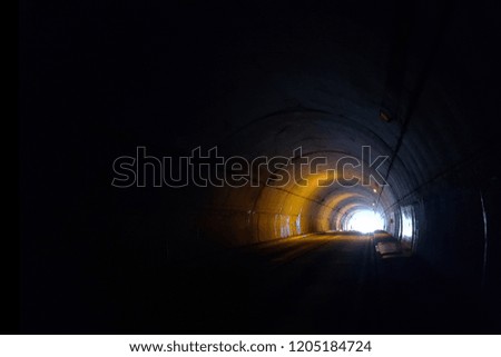 The dark half-circle subway tunnel that have a light at the end of the tunnel exit, shown as abstract background.