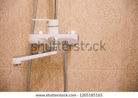 In the bathroom, open shower mixer has attached to the wall bracket, tinted black and white image, vertical format.