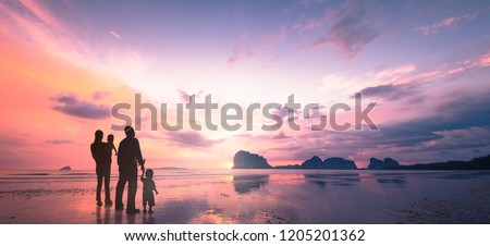 Family Day concept: Father, mother and two son over water on beach sunrise background. Pak Meng Beach, Trang, Thailand, Asia