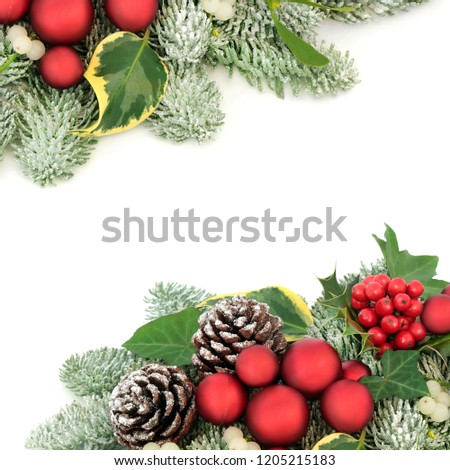 Christmas background border with red bauble decorations, holly berries, snow covered spruce pine, ivy, pine cones and mistletoe on white background with copy space.