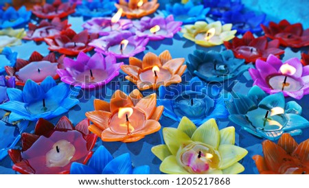 Multi colored lotus candles floating on water for Buddhists worship in Thailand. 