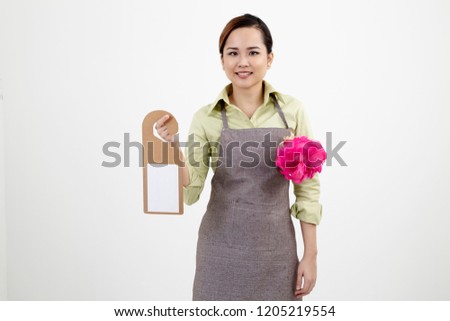 woman wearing apron holding a blank door tag and duster