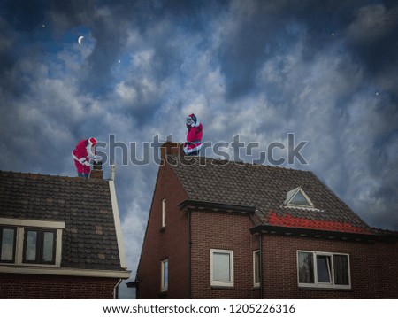 Two Santa Clauses in a traditional costume working on the roof of a house on the dark night sky background. Cooperation concept.