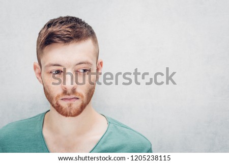 Sad young man on a gray background. Closeup portrait.