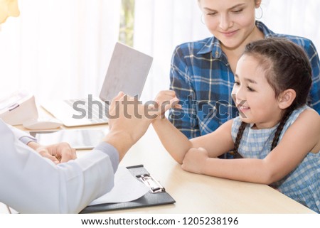 Pediatrician (doctor) man giving fist bump (High Five To),reassuring and discussing kid at surgery.Mother Caucasian and kid smiling in hospital room.Copy space.

