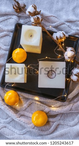 Inspiration winter still life decor cotton orange tangerines and candles on black tray cosy fairy lights on cozy gray plaid. Christmas card idea. Flat lay top view copy space. Concept Color 2021.