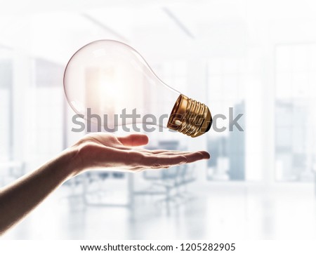 Close of male palm holding glass light bulb on interior background